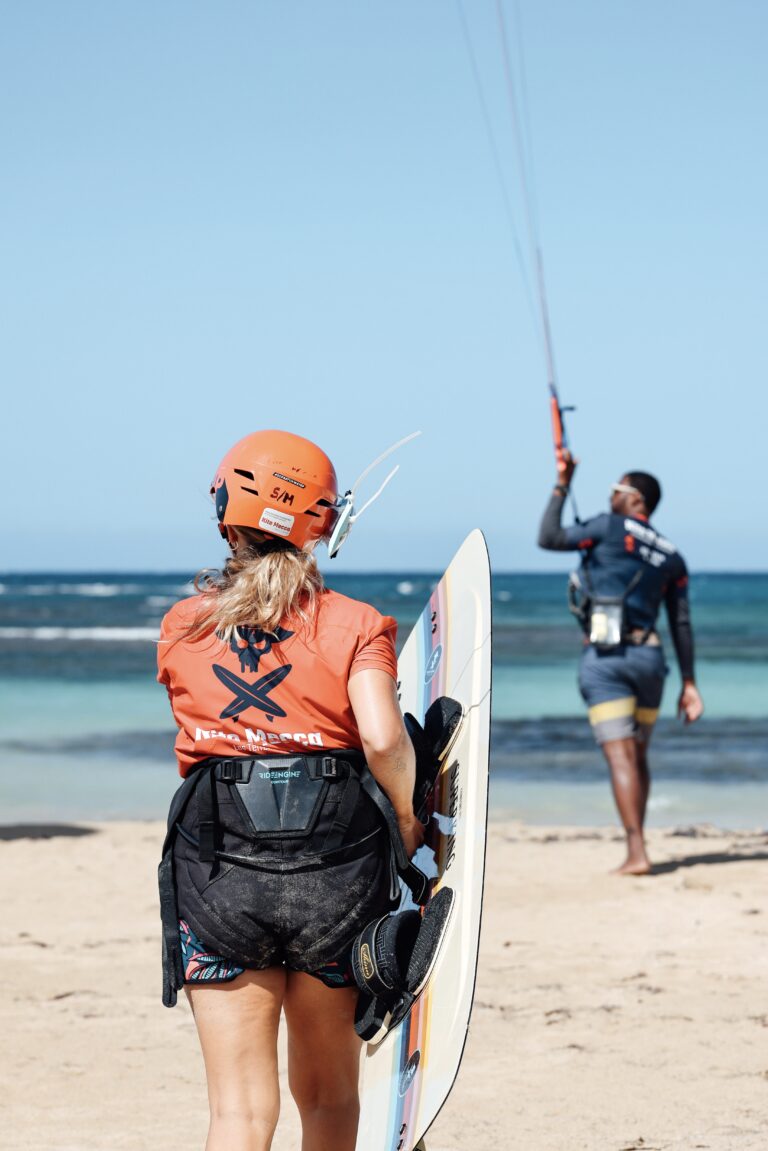 kitesurfing student with a kiteboard is following its instructor